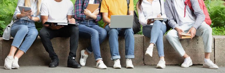 Schüler sitzen nebeneinander auf einer Mauer